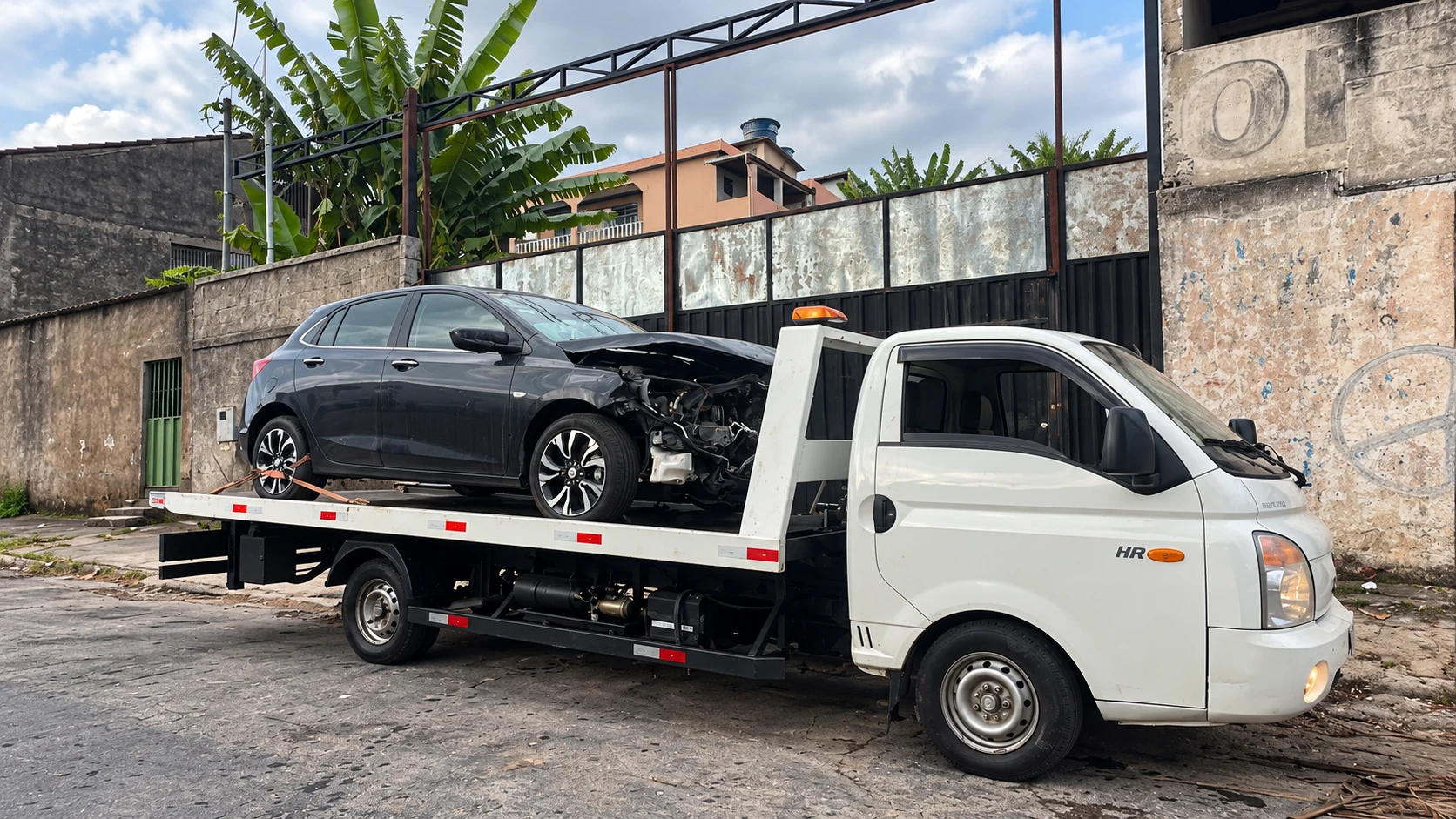 Avante Auto Socorro transportando um automóvel preto com avaria na parte frontal.